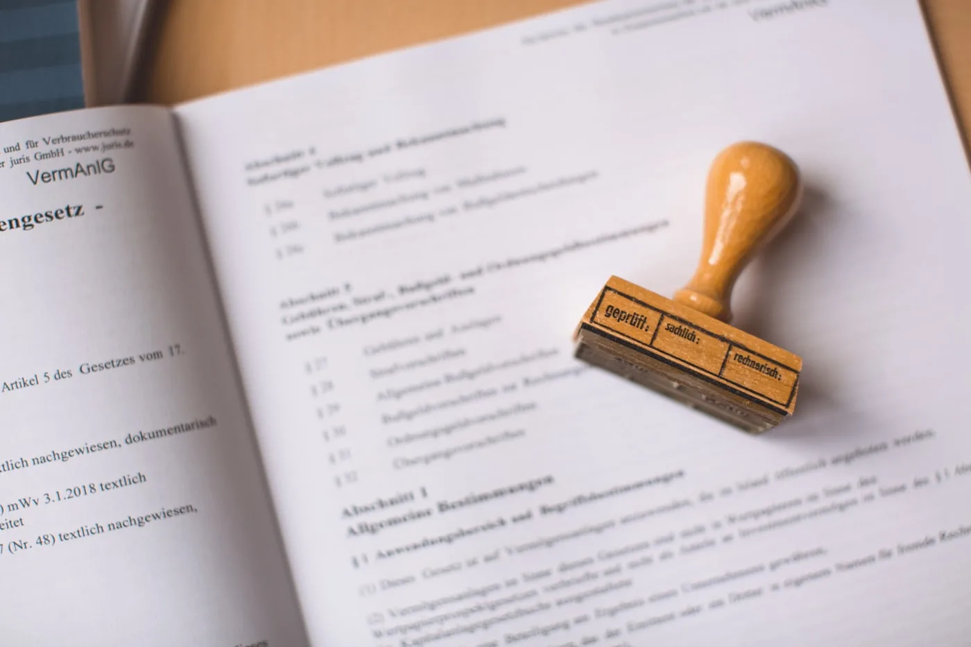 A wooden stamp resting on an open statute, the page showing a list of numbered sections.