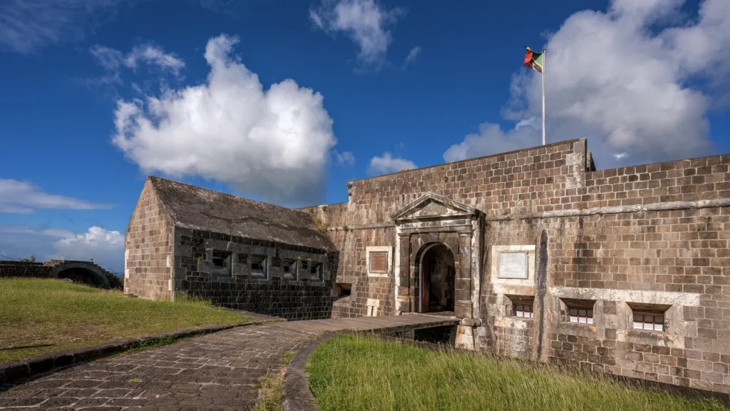 Cổng đá của pháo đài Brimstone Hill trên đảo Saint Kitts, cờ Saint Kitts and Nevis bay trên tường thành dưới trời xanh
