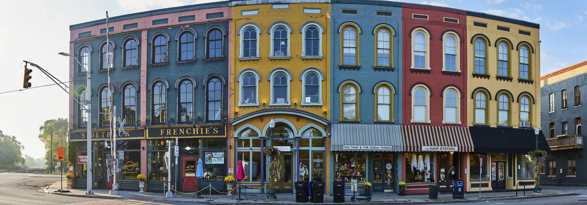 A row of old, brightly painted shopfronts with awnings in an American small town, photographed in the early morning.