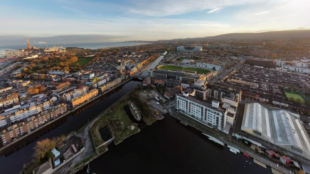 Dublin from above in late afternoon light, with Grand Canal Dock, rows of housing, the Aviva Stadium and Dublin Bay in the distance