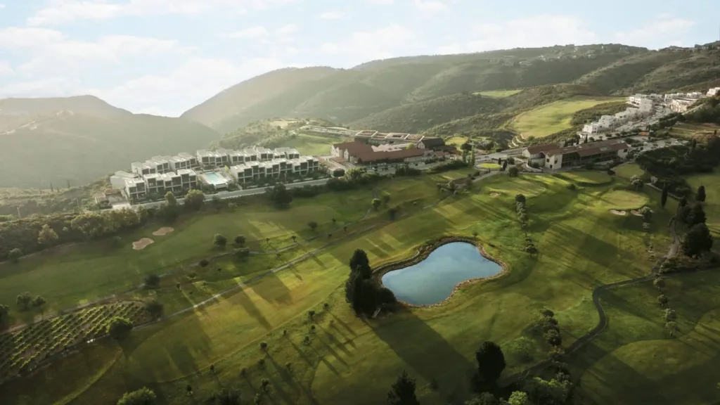 Aerial view of the golf course and a pond with hills behind