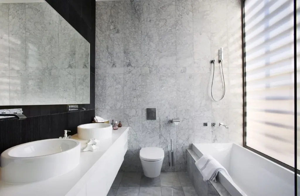 Marble bathroom with a freestanding tub, twin basins and a sunlit window