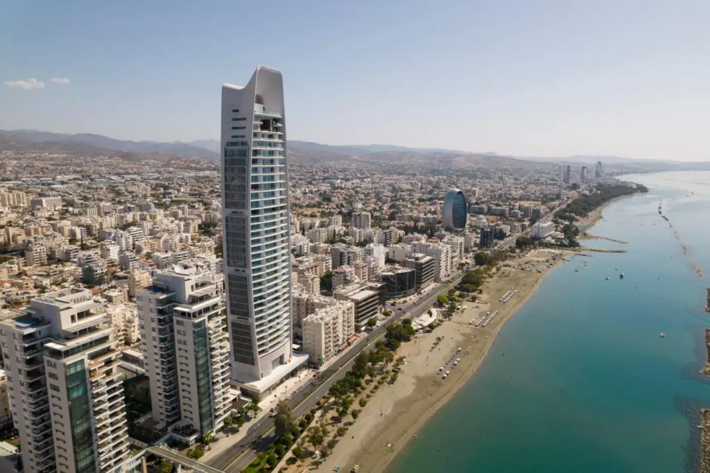 Aerial view of the ONE tower rising above the Limassol seafront, beach and coastal road