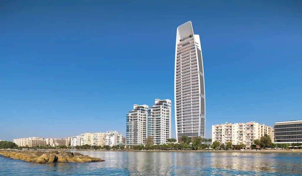 The ONE tower and neighbouring apartment blocks seen across the water from a rocky shoreline