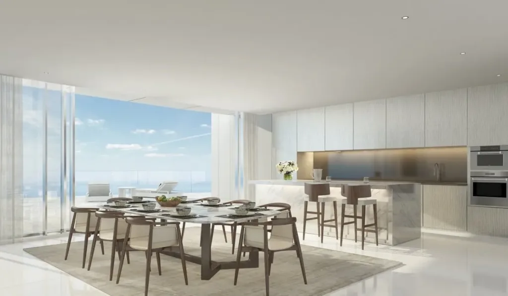 Kitchen with breakfast bar and dining table facing the sea through glass walls