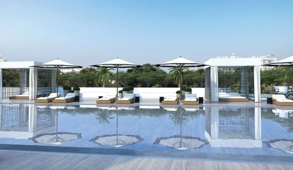 Pool deck with loungers, parasols and cabanas reflected in the water