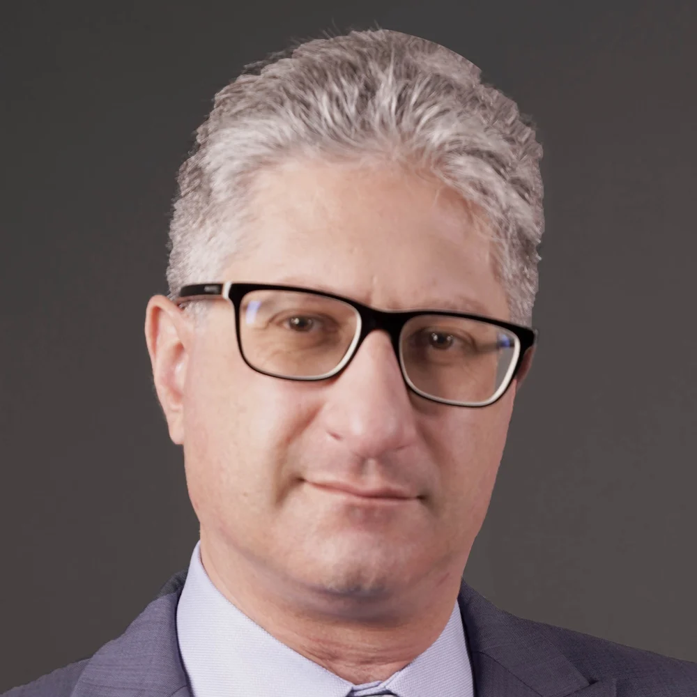 Portrait of Dr. Stephan Gauci in glasses and a grey suit