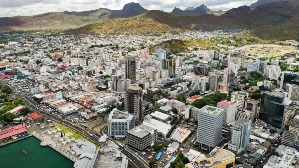 Central Port Louis from above, with office towers, the harbour front and the mountains behind the city