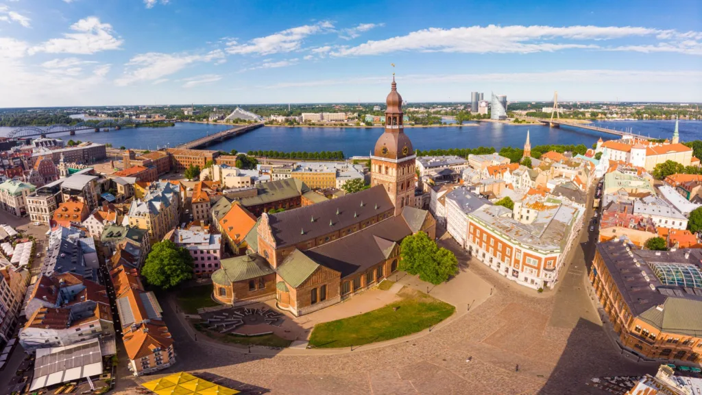Riga's Old Town from above, with the Dome Cathedral and its square, red and green roofs, and the Daugava river with its bridges behind.
