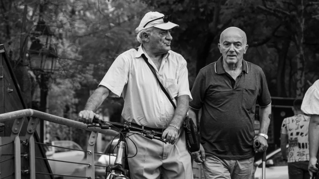 Two men walk with a bicycle along a street in Tirana, Albania