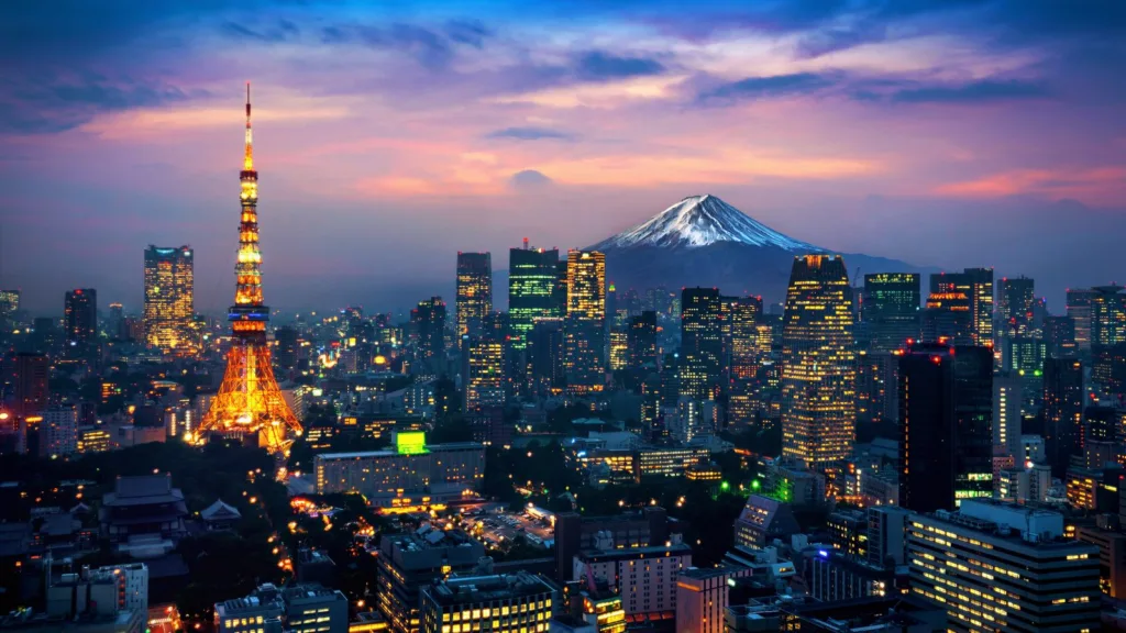 Tokyo at dusk with the lit Tokyo Tower among office towers and Mount Fuji on the horizon