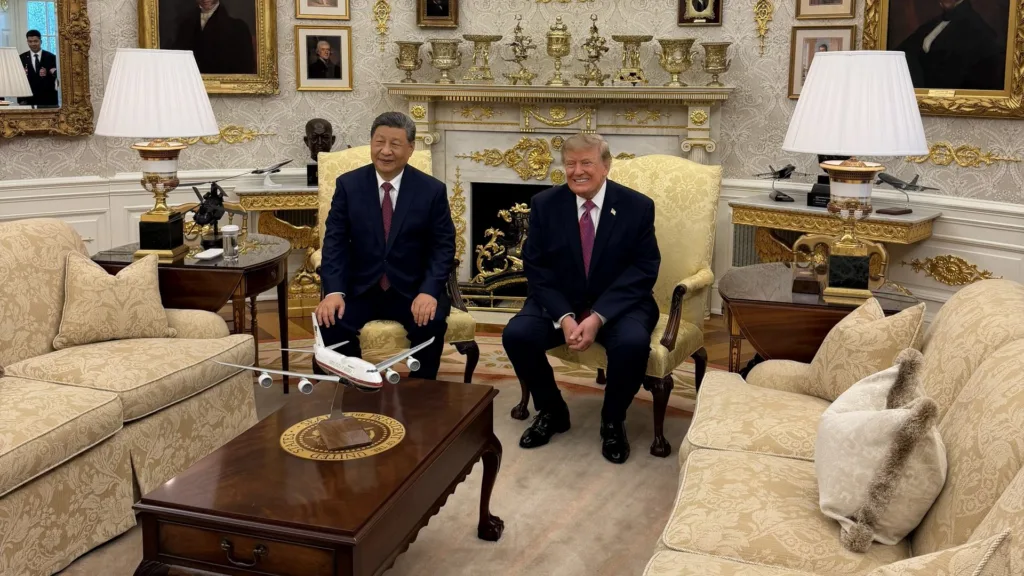 Xi Jinping and Donald Trump seated side by side in armchairs in the Oval Office, with portraits on the wall behind them and a model aircraft on the coffee table