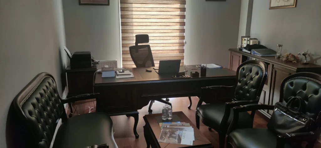 An office at Selman YANI Law Firm with a wooden desk, a laptop and black leather chairs