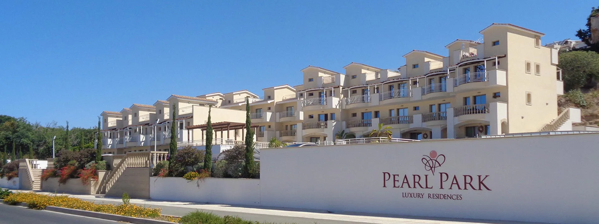Lối vào khu Pearl Park Residences với biển tên và các dãy nhà màu kem