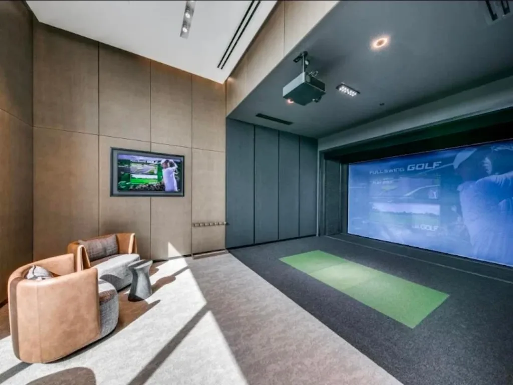 Phòng giải trí có màn hình mô phỏng golf, ghế bành da nâu và tường ốp vải