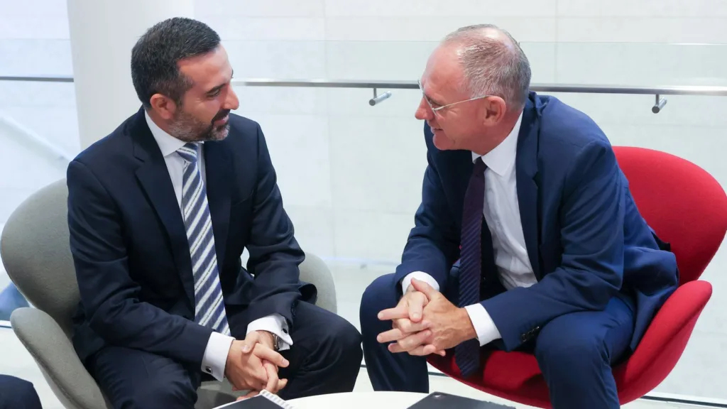 Cyprus's deputy migration minister Nicholas Ioannides, left, in a grey armchair, talks with Austria's interior minister Gerhard Karner, seated in a red armchair, beside a low white table