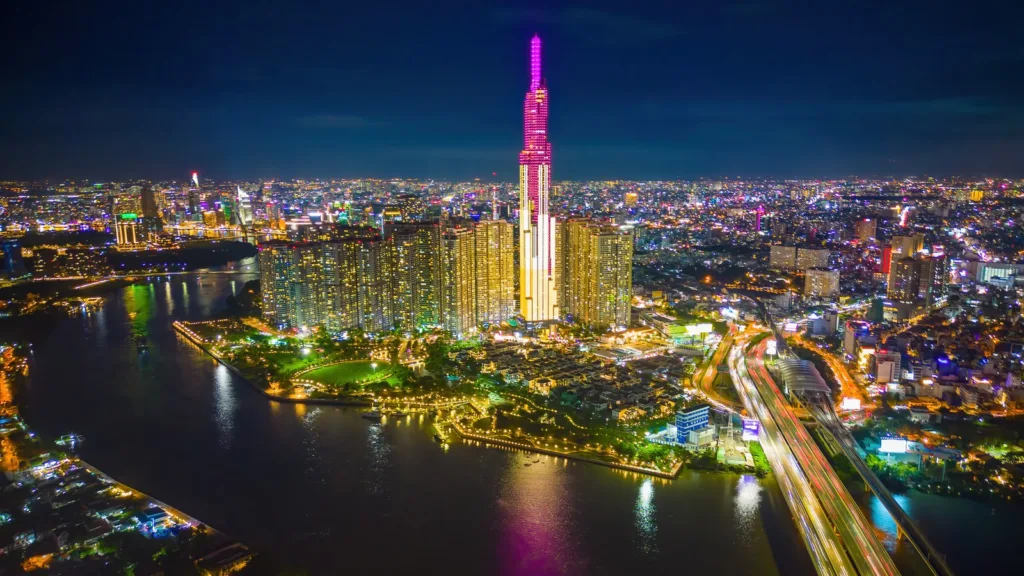 Ho Chi Minh City at night from above, with the lit Landmark 81 tower, apartment blocks and the Saigon River