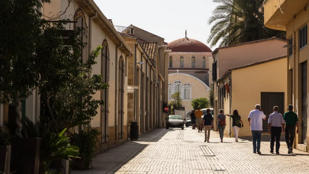 Người đi bộ trên con phố lát đá ở khu phố cổ Nicosia, hướng về một nhà thờ mái vòm đỏ